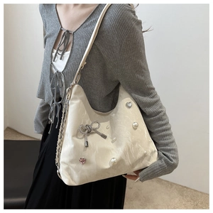 Detail of cream pleated shoulder bag with pearl accents and a crystal bow decoration