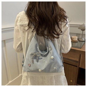 Detail of light blue shoulder bag with pearl accents and sparkling crystal butterfly tassel