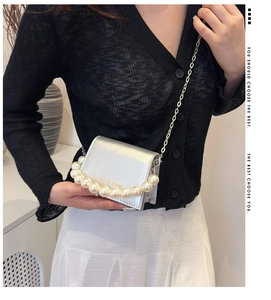 Close-up of silver mini crossbody bag with pearl handle and metal chain strap