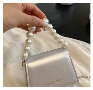Close-up of silver mini crossbody bag featuring large pearl handle and metal chain