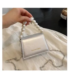 Detail of silver mini bag with white pearl handle and shiny metallic chain strap