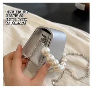 Detail of the silver mini bag featuring a detachable metal chain strap and pearl handle