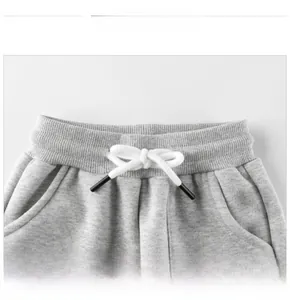 Detail of gray joggers featuring an elastic ribbed waistband and white drawstrings
