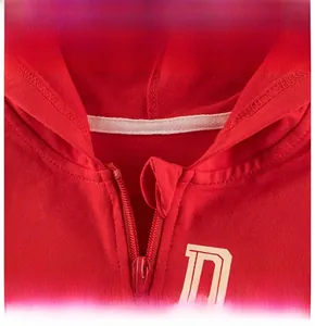 Détail du sweat à capuche rouge montrant la texture du coton et la fermeture éclair