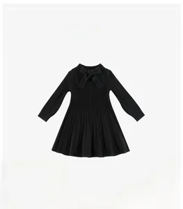 Close-up of black knitted girl's dress featuring a bow tie and vertical ribbed texture