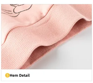 Detail view of pink sweatshirt ribbed hem featuring artistic black lettering patterns
