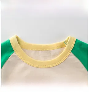 Detail of yellow ribbed crew neck and green raglan sleeve on cotton kids shirt
