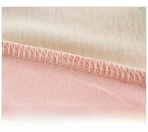 Dettaglio ravvicinato delle cuciture overlock su tessuto di cotone rosa e beige