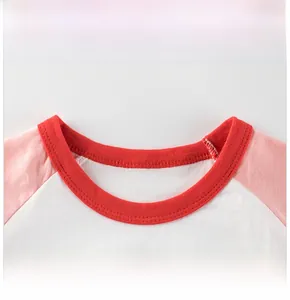 Détail du col rond rouge sur un t-shirt à manches raglan en coton pour filles