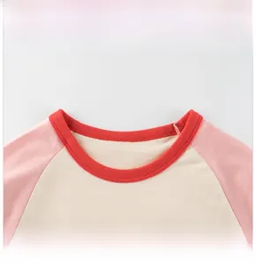 Détail du col rond rouge sur t-shirt manches raglan pour enfant en rose et blanc cassé