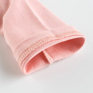 Dettaglio del polsino della maglietta rosa in cotone con cuciture overlock rifinite