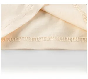Vue macro détaillée de l'ourlet à double couture sur un t-shirt en coton beige pour enfants