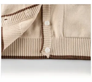Detailed close-up of knit cardigan hem with brown fringe trim and ribbed texture