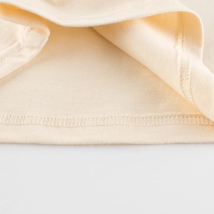 Zoom sur l'ourlet en maille de coton avec surpiqûre sur le t-shirt raglan beige ours