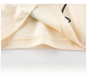 Close-up of fine double-needle stitching on the hem of a cream cotton toddler t-shirt