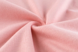 Gros plan détaillé du tissu en jersey de coton rose montrant la texture douce et lisse