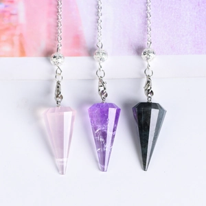 Three conical natural stone crystal pendants with silver metal chains on a soft background