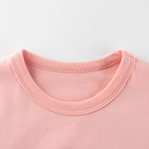Gros plan d'un t-shirt rose en coton pour enfants avec col rond côtelé et coutures précises