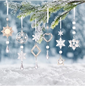 Set of 6 acrylic snowflake and crystal pendants hanging on snowy pine branches