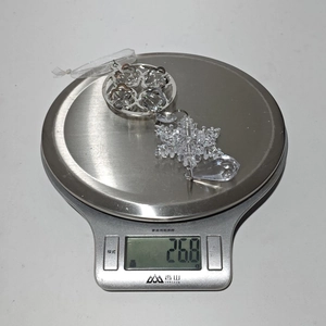 Macro shot of a snowflake crystal ornament weighing 26.8g on a digital kitchen scale