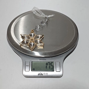 Macro view of a gold hexagonal star crystal ornament weighing 17.5g on a scale