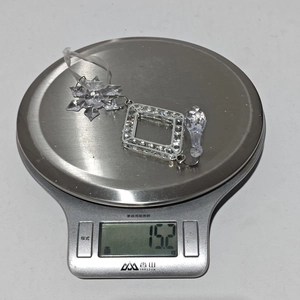 Close-up of clear acrylic snowflake and drop ornaments weighing 15.2g on a scale