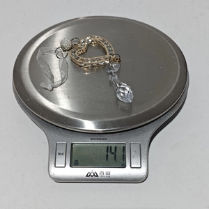 Detailed view of a crystal heart ornament with gold trim on a digital scale weighing 14.1g