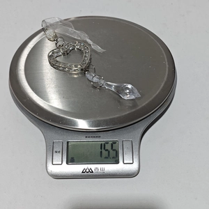 Detailed shot of an acrylic heart ornament with crystals on a digital scale weighing 15.5g