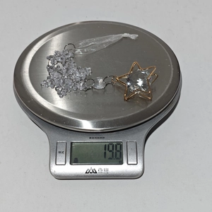 Detailed view of acrylic snowflake and star ornament on scale showing 19.8g weight
