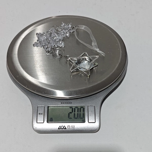 Transparent acrylic snowflake crystal ornament on a kitchen scale weighing 20 grams