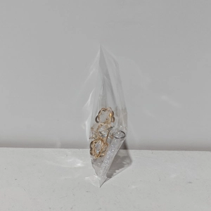 Macro detail of gold flower claw clip with hollowed-out design in clear packaging