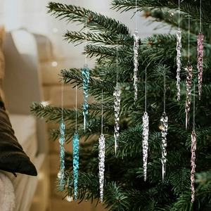 Macro detail of twisted acrylic Christmas icicle pendants on a green festive tree branch