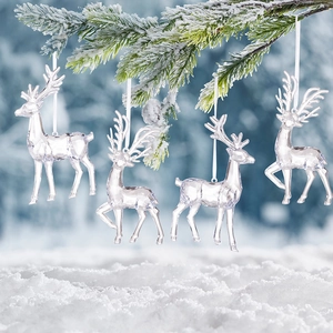 Close-up of four transparent acrylic reindeer ornaments hanging on snowy pine branches