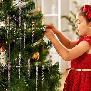 Pink translucent acrylic icicle ornament hanging on a Christmas tree by a girl
