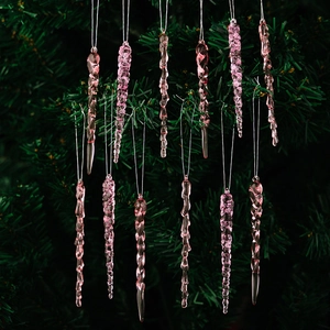 Macro detail of translucent pink acrylic icicle ornaments on green Christmas tree branches