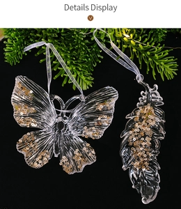 Detail of clear acrylic butterfly and feather ornaments with gold sequins on pine needles