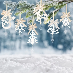 Detailed view of white iron snowflake and reindeer ornaments hanging on a snowy pine branch