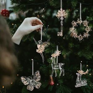 Close-up of clear acrylic Christmas ornaments with gold glitter on a festive tree
