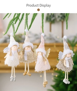 Detail of four plush pink and white Christmas angel ornaments hanging on a pine tree branch