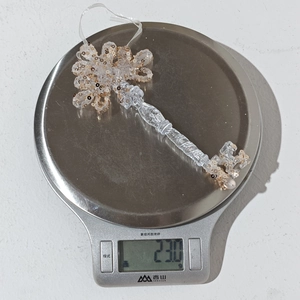 Macro shot of 23g acrylic key ornament with sequins on scale for weight reference