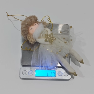 Detail view of a pink plush angel ornament on a scale weighing exactly 11.7 grams