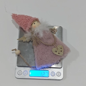 Pink plush angel Christmas ornament with gold heart on a digital scale for weight display