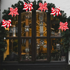 Detail of red and white striped Christmas bow with spiral candy center on a green wreath