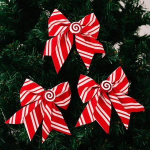 Detail of three red and white striped Christmas bows with peppermint buttons on a tree
