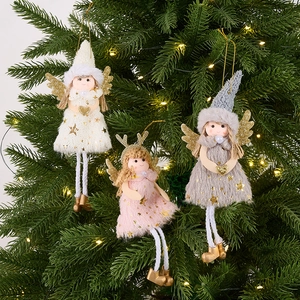 Three plush angel ornaments with gold sequins hanging on a Christmas tree with warm lights
