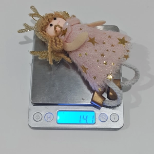 Detailed view of pink plush angel ornament with golden antlers on a digital weight scale