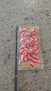 Close-up of red and white striped Christmas candy bows set with measuring tape reference