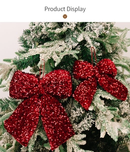 Close-up of red sequined Christmas bows hanging on a snow-covered pine tree branch