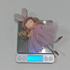 Pink fairy angel doll with bunny ears and gold wings on a digital scale weighing 7.8g