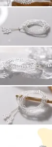 Macro detail of multi-layer white crystal beaded bracelet with silver metal pendant